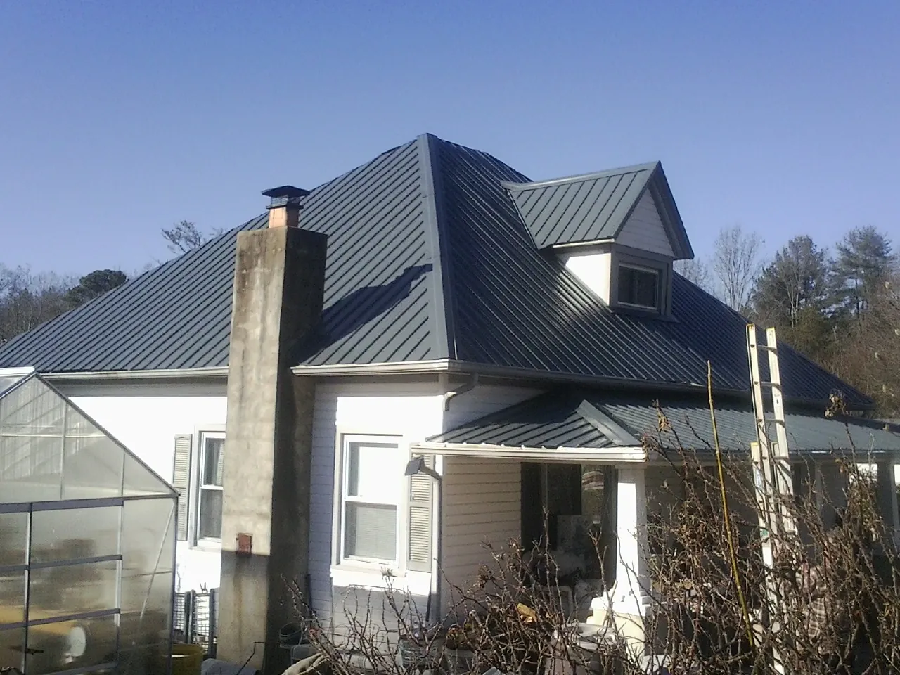 Dark blue standing seam metal roof on a white farmhouse with dormer — Slate & Tile Roof Repair by Roofing Brothers in Salineville