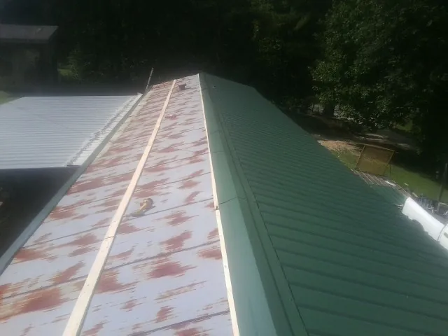 Old rusted panels beside newly installed green metal roofing — Wind Damage Roof Repair by Roofing Brothers in Salineville