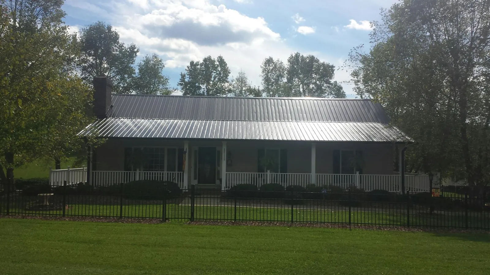 Gray metal roof on a brick ranch with a full width front porch — Gutter Guard Installation work by our crew in Salineville
