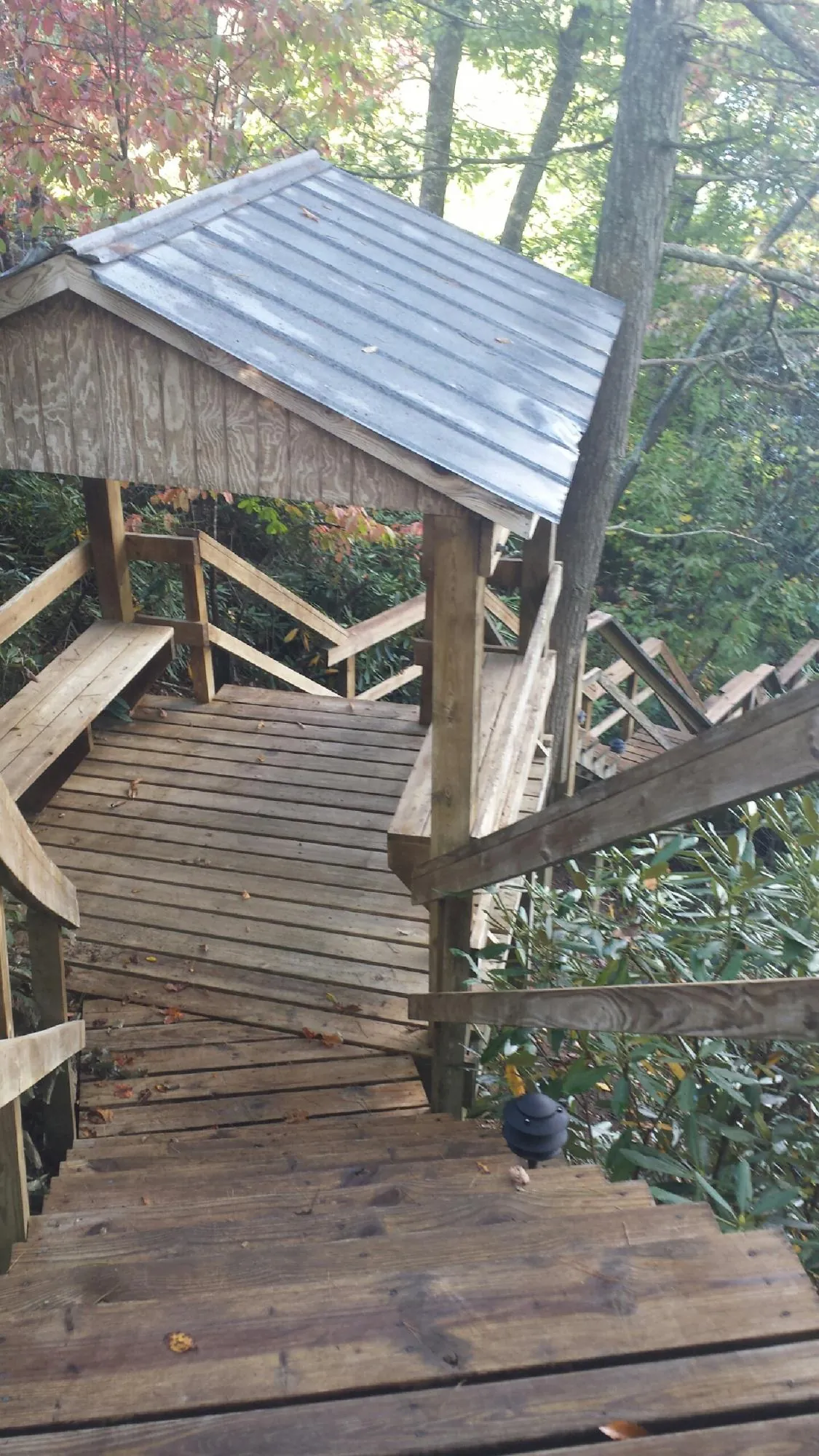 Metal roofed shelter over wooden steps on a wooded walkway — Skylight Repair & Installation work by our crew in Salineville