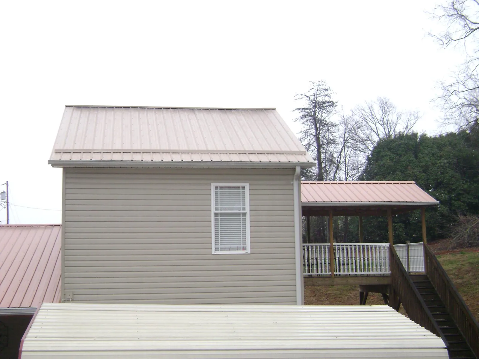 Tan metal roofs on a two story addition and attached porch, from a Roof Replacement job in Salineville