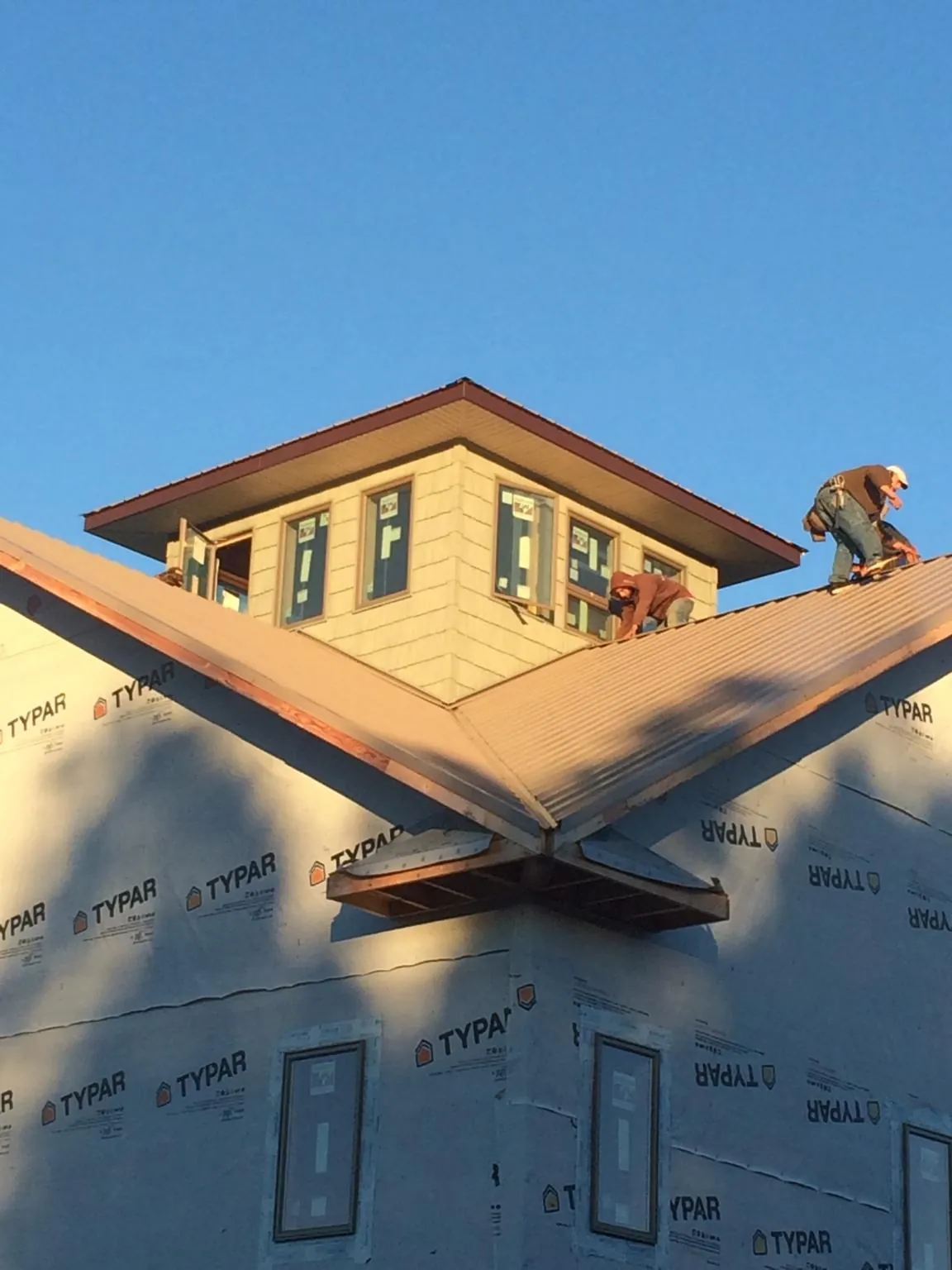 Roofers working around a rooftop cupola on a new metal roof at sunset — Roof Waterproofing in Salineville by Roofing Brothers